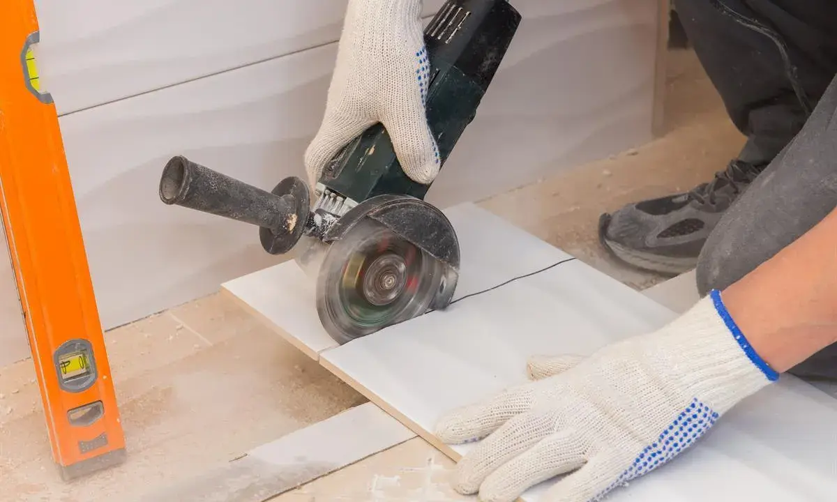 Ręczne cięcie płytek kątówką to jeden z domowych sposobów na precyzyjne dopasowanie materiału. Poziomica pomaga w dokładności.