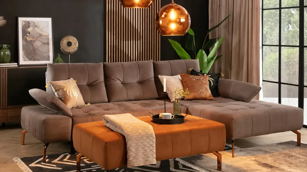 Elegancki salon z brązową kanapą w kolorze taupe jaki to kolor. Miękki dywan i pomarańczowa pufa dodają ciepła.