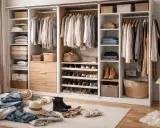 Zorganizowana garderoba z szafami pod zabudowę IKEA. Ubrania wiszą na wieszakach, a buty i akcesoria są poukładane na półkach i w koszach.