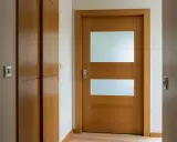 Jak przerobić stare drzwi z szybą na nowoczesne? Drewniane drzwi z dwoma matowymi przeszkleniami i metalową klamką.