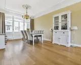Drewniana podłoga w jadalni, panele ułożone równolegle do okna, tworzą ciepłą atmosferę.