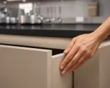 Dłoń otwiera szufladę z frontami kuchennymi antifinger. Czystość i elegancja w kuchni.
