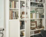Książki, globusy i dekoracje tworzą przytulną domową biblioteczkę w małym mieszkaniu.