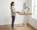 Kobieta pracuje przy biurku, które ma idealną wysokość, zapewniając ergonomiczne ustawienie ramion i wzroku.