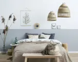 Przytulna sypialnia w stylu boho. Pokój dwukolorowy z łóżkiem, plecionymi lampami i ozdobami z naturalnych materiałów.