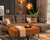 Elegancki salon z brązową kanapą w kolorze taupe jaki to kolor. Miękki dywan i pomarańczowa pufa dodają ciepła.