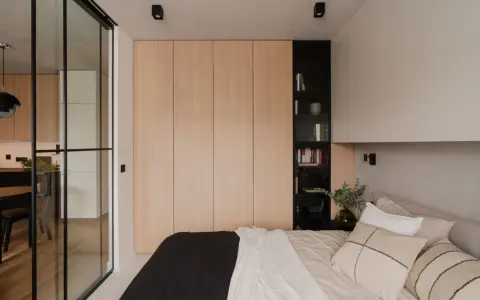 Jasne, oto propozycja:

Sypialnia z łóżkiem i szafą z frontami ikea pax w naturalnym drewnie. Obok czarna, otwarta półka z książkami.