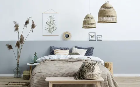 Przytulna sypialnia w stylu boho. Pokój dwukolorowy z łóżkiem, plecionymi lampami i ozdobami z naturalnych materiałów.