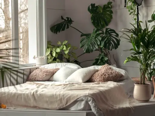 Przytulna sypialnia w stylu urban jungle. Duże liście monstery i palmy tworzą zieloną oazę wokół łóżka.
