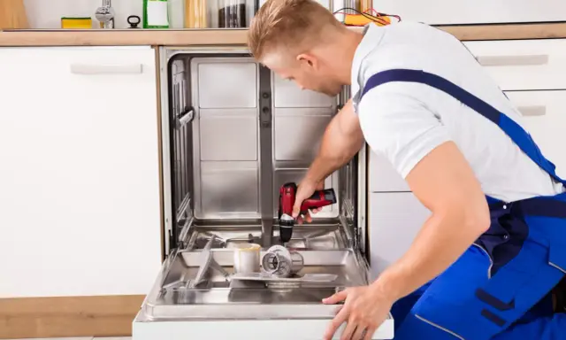 Fachowiec montuje front do zmywarki Ikea, używając wiertarko-wkrętarki.