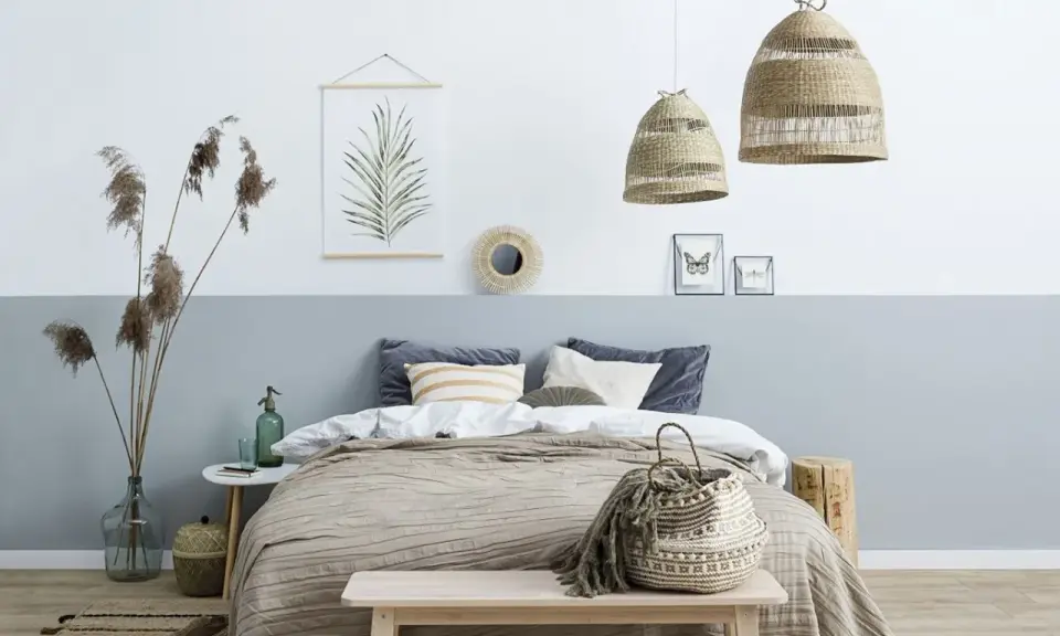 Przytulna sypialnia w stylu boho. Pokój dwukolorowy z łóżkiem, plecionymi lampami i ozdobami z naturalnych materiałów.