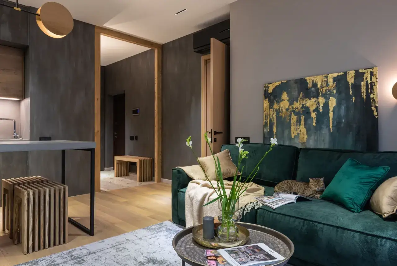 Elegancki salon w butelkowej zieleni i drewnie. Kot odpoczywa na kanapie, a w wazonie stoją świeże kwiaty.