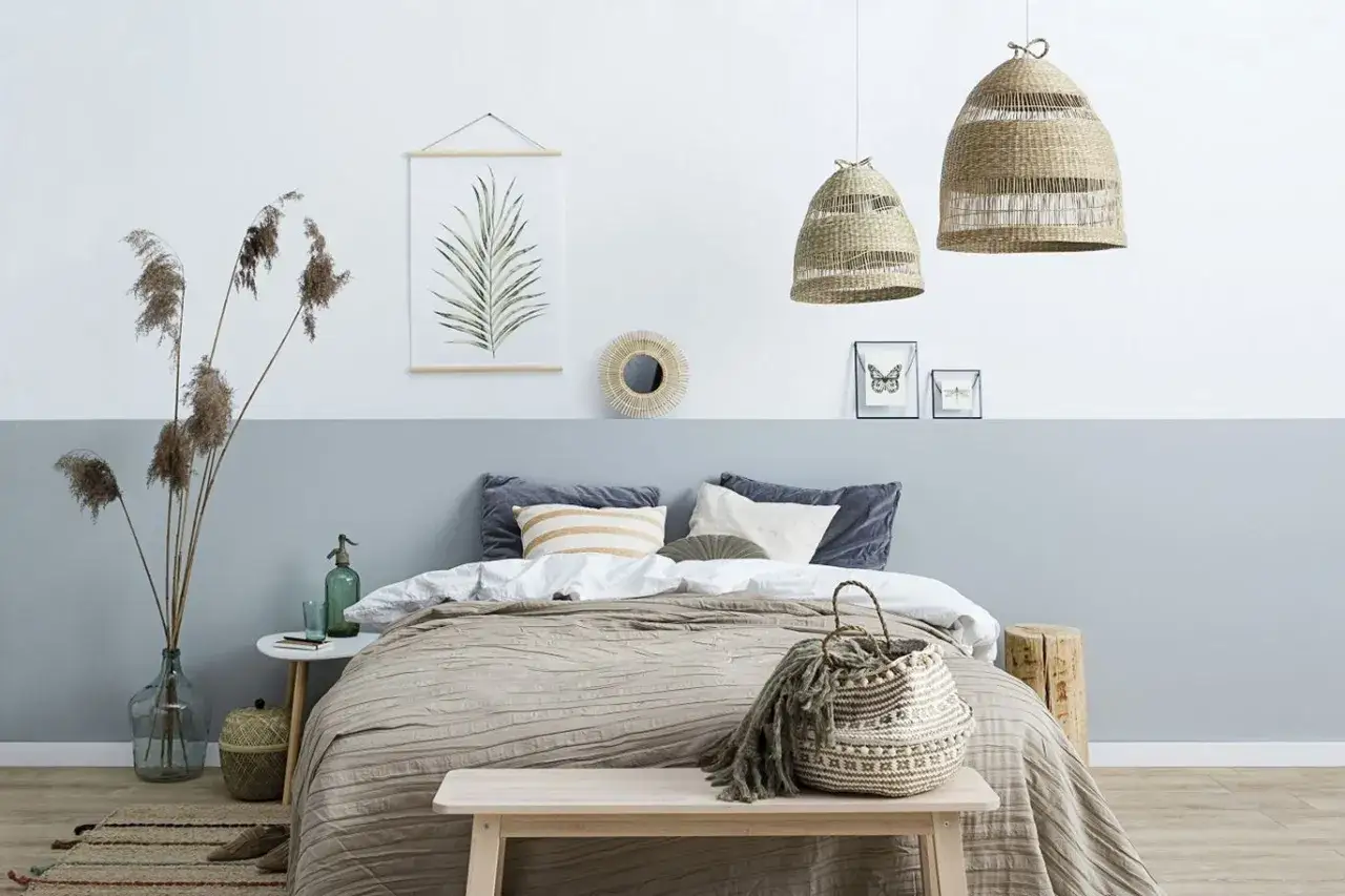 Przytulna sypialnia w stylu boho. Pok&oacute;j dwukolorowy z ł&oacute;żkiem, wiklinowymi lampami i ozdobami z naturalnych materiał&oacute;w.